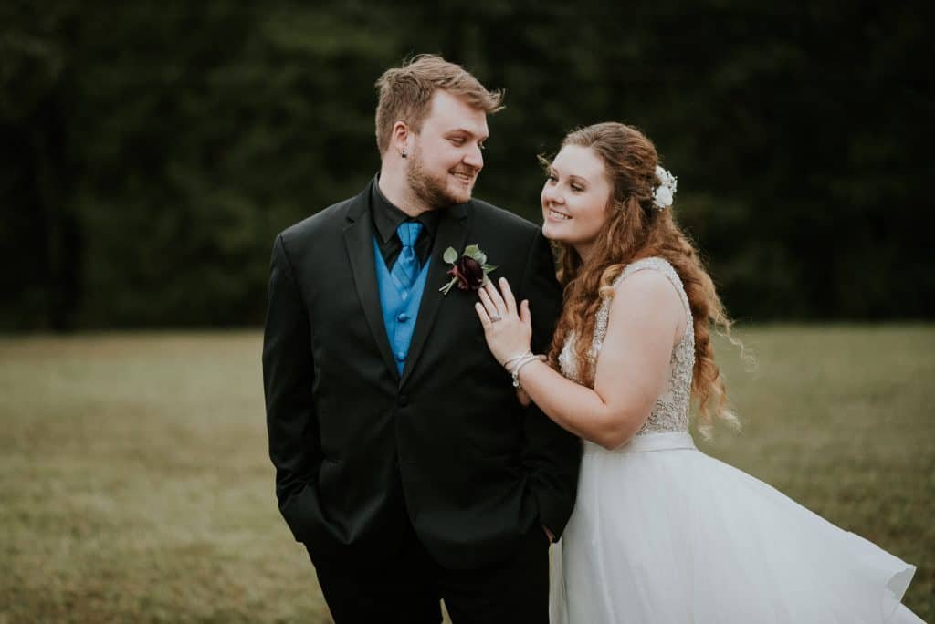 bride and groom looking at each other outside woodsy area