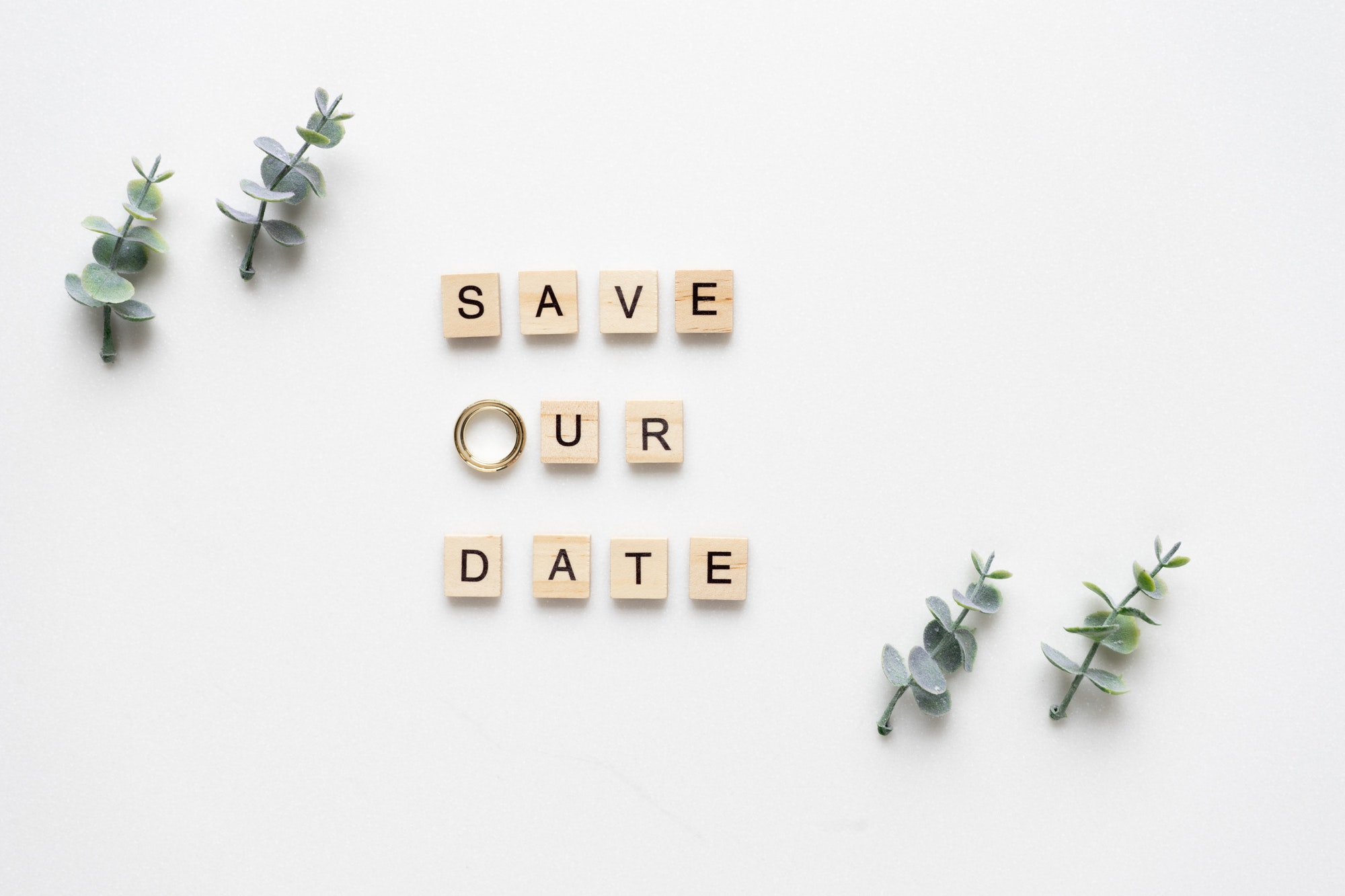 Wooden letters spelling save our date, oregano branches and wed
