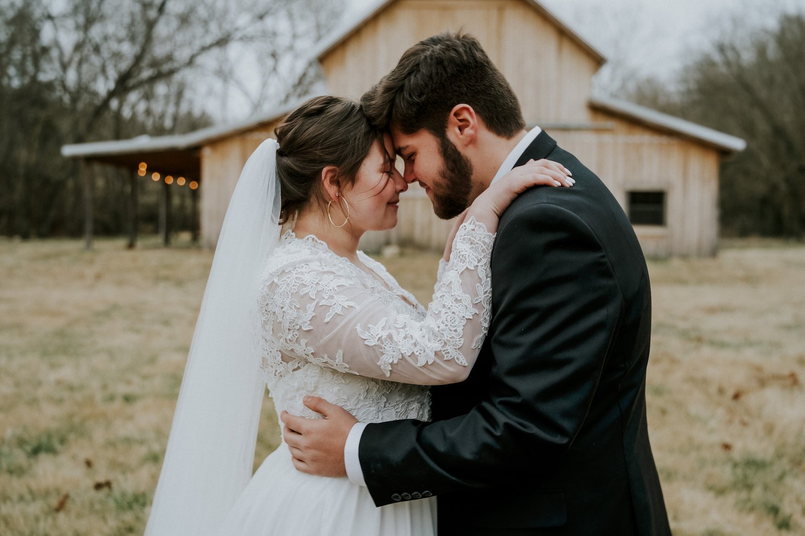 Wedding photo of Bride and groom forehead to forehead in front of Armas barn in Arkansas