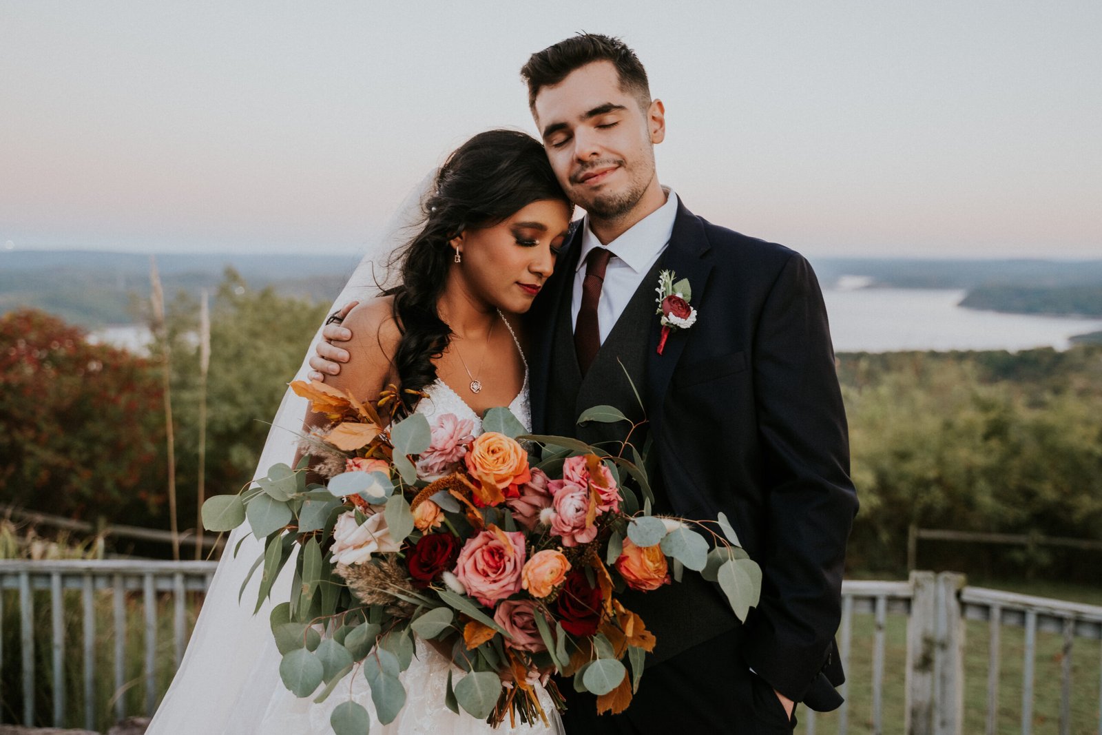 groom hugging bride lake view