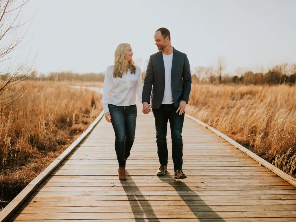 The couple walking hand in hand along a trail in Osage Park, showcasing the park's beauty.