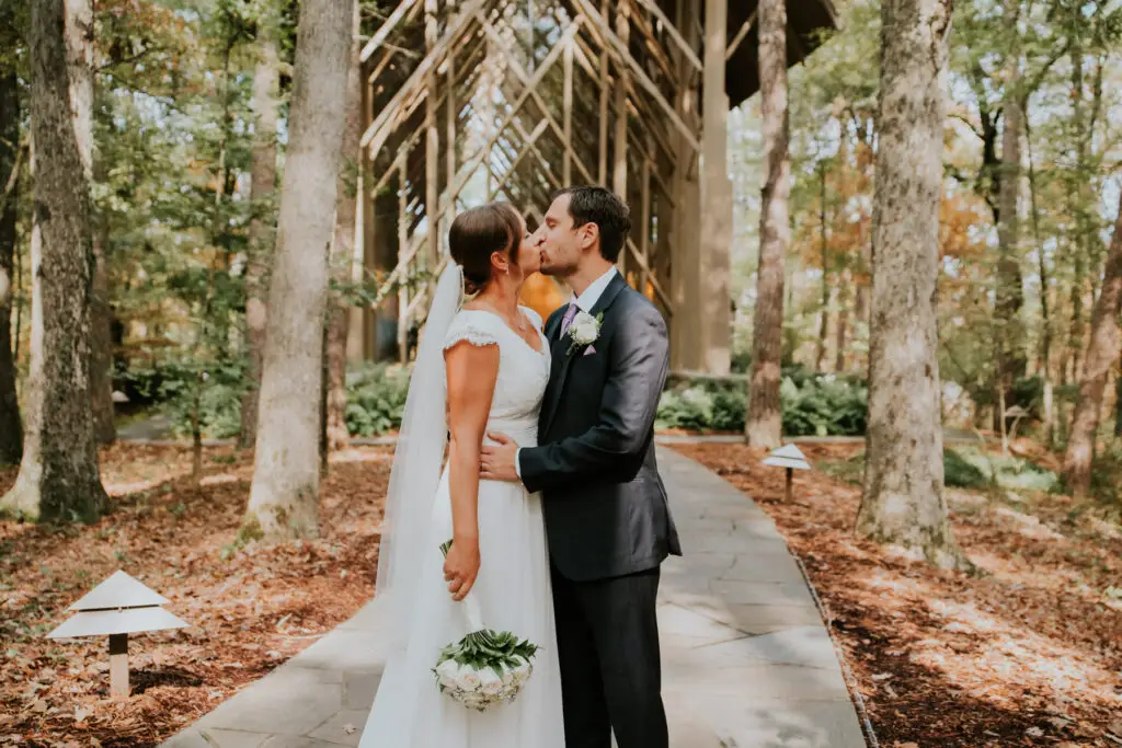 Bride and groom kiss among autumn trees at an outdoor Northwest Arkansas wedding venue