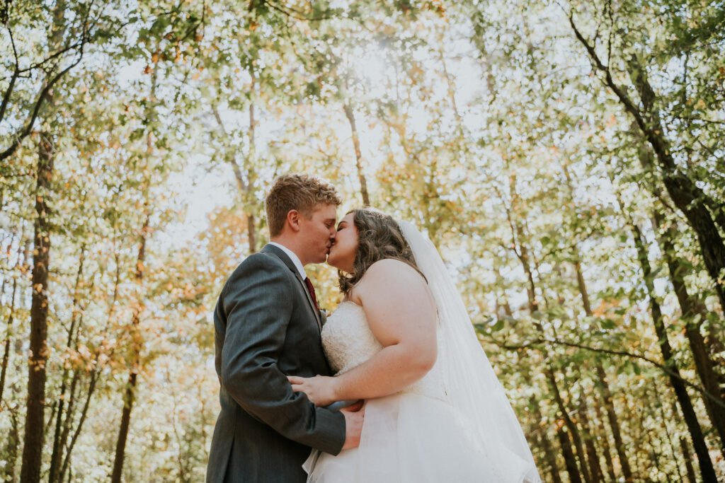 Bride and groom kiss in the woods after their elopement at Cooper Chapel in Bella Vista, Arkansas