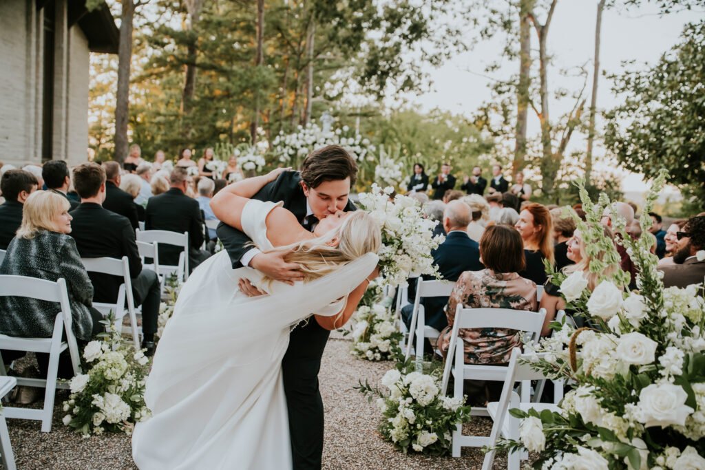Bride and groom kiss at the end of the aisle during their outdoor wedding ceremony