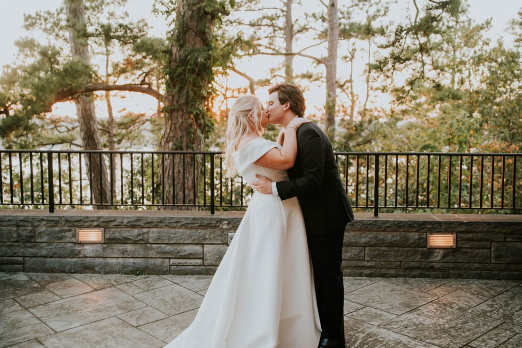 Bride and groom embracing at golden hour on a stone terrace overlooking the Ozarks