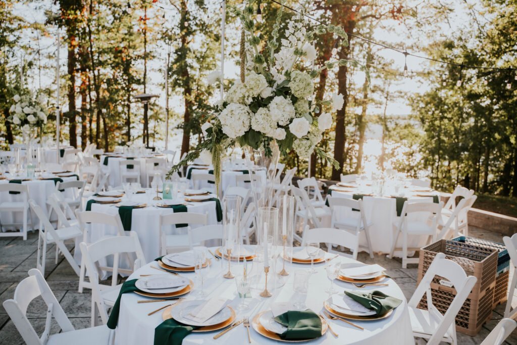 Reception tables set with white florals and greenery under the trees