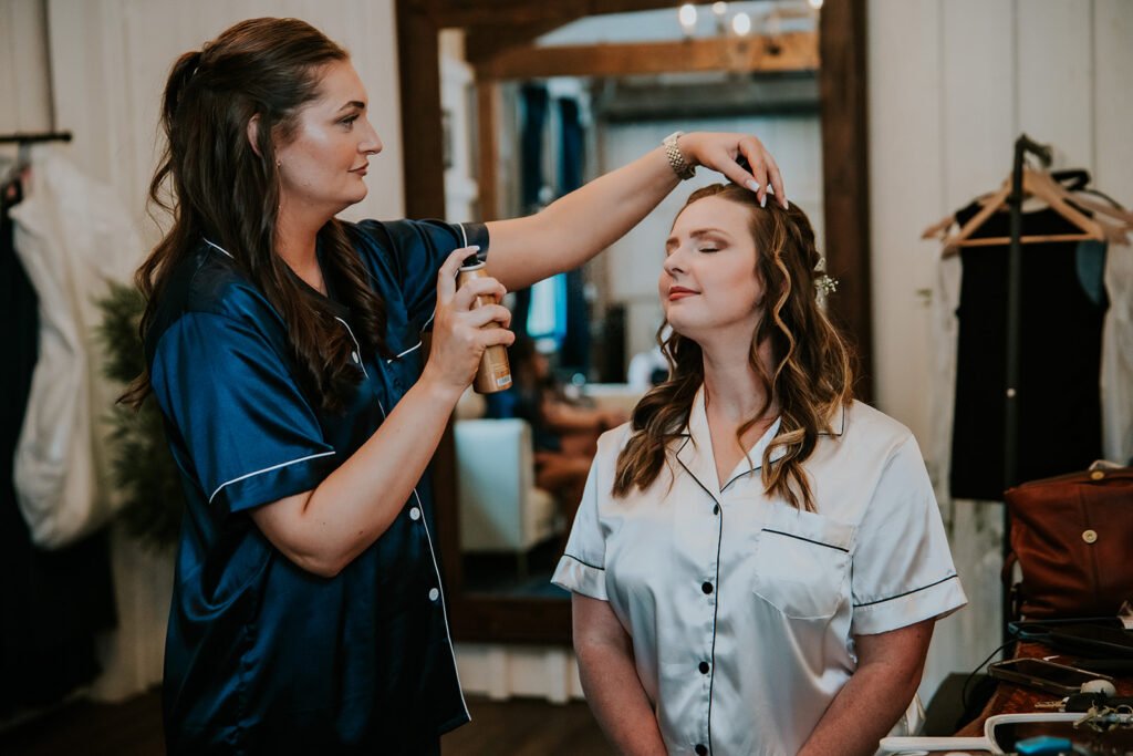 Bridesmaid helping the bride get ready in the bridal suite at Holland Barn