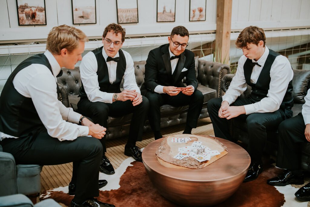 Groomsmen playing cards in the loft above the great room at Holland Barn