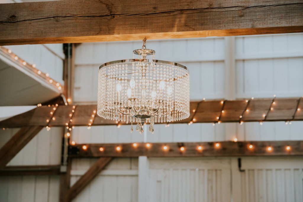 Holland Barn reception space with chandelier and string lights above long tables