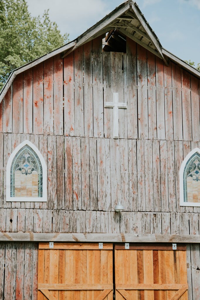 Cross and arched stained glass windows on the front of Amy's Chapel at Holland Barn