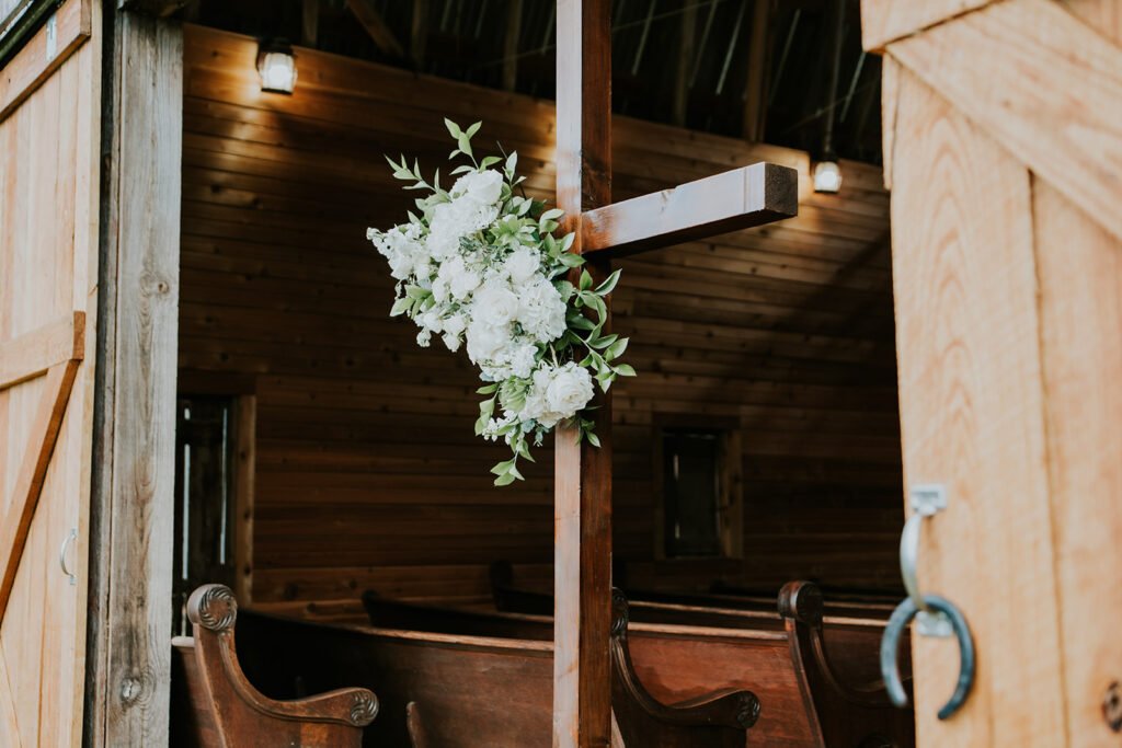 Wooden pews and florals inside Amy's Chapel at Holland Barn in Highfill, Arkansas