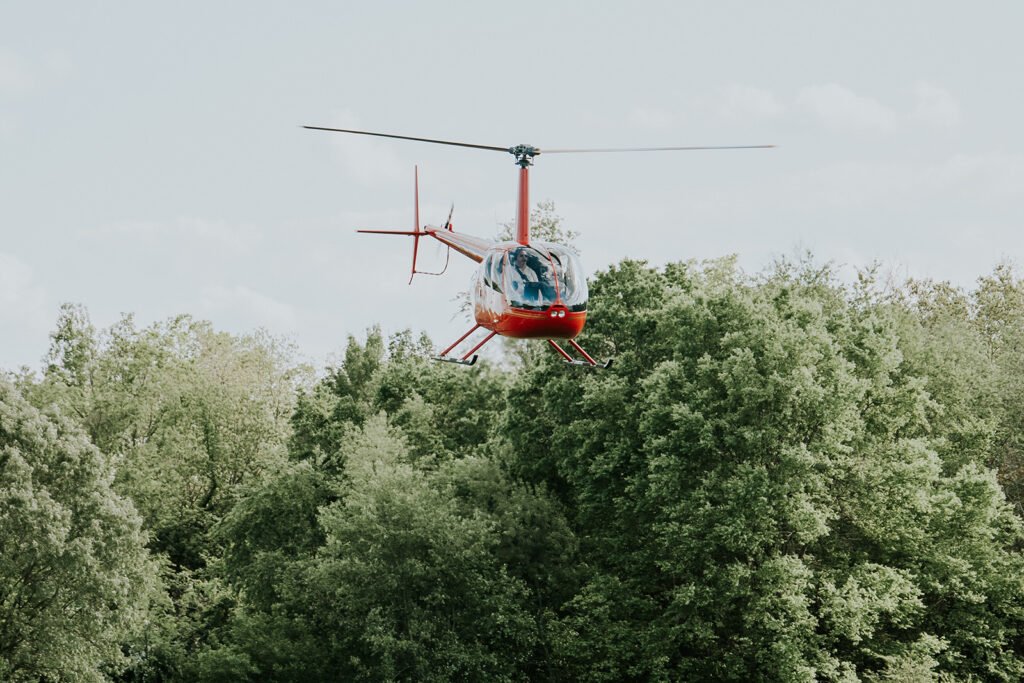 Helicopter lifting off over the trees after a Holland Barn wedding send off