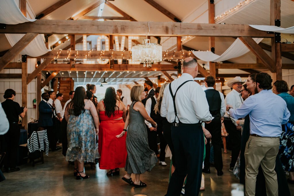 Wedding guests filling the dance floor at a Holland Barn reception in Highfill, Arkansas