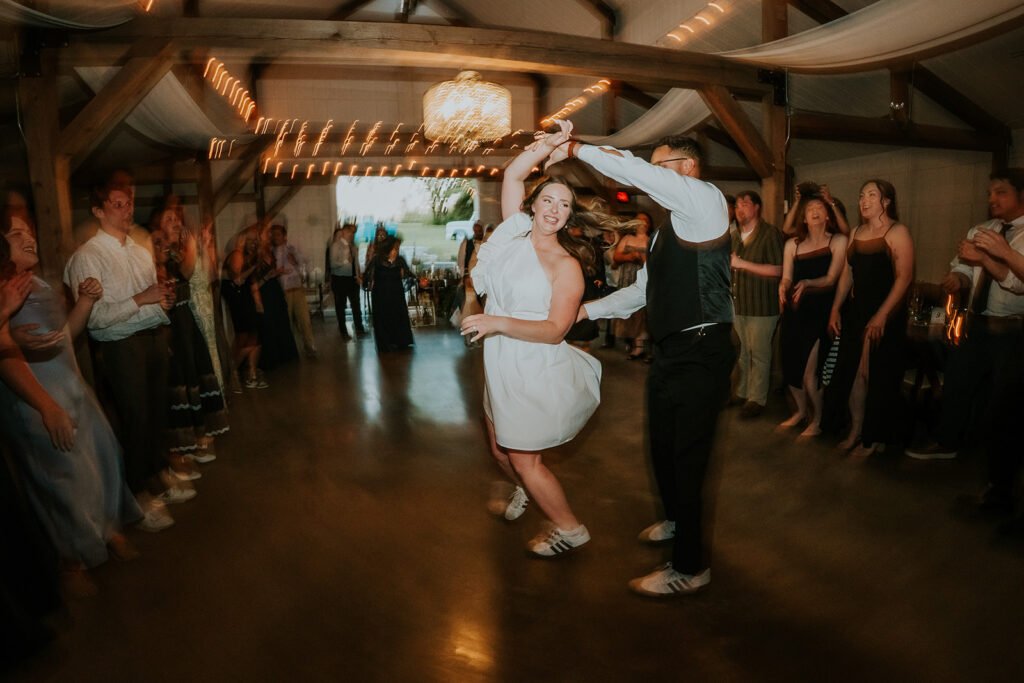 Guests dancing across the open reception floor under string lights at Holland Barn