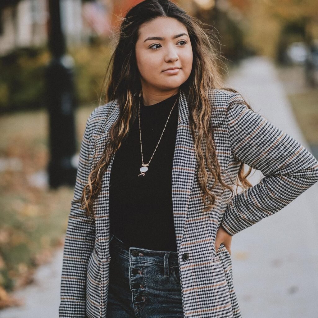 Senior girl in a houndstooth blazer on a downtown sidewalk, NWA senior pictures