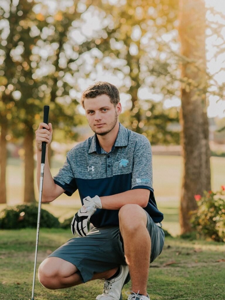 Senior guy kneeling with a golf club on the course, golf senior pictures in Northwest Arkansas