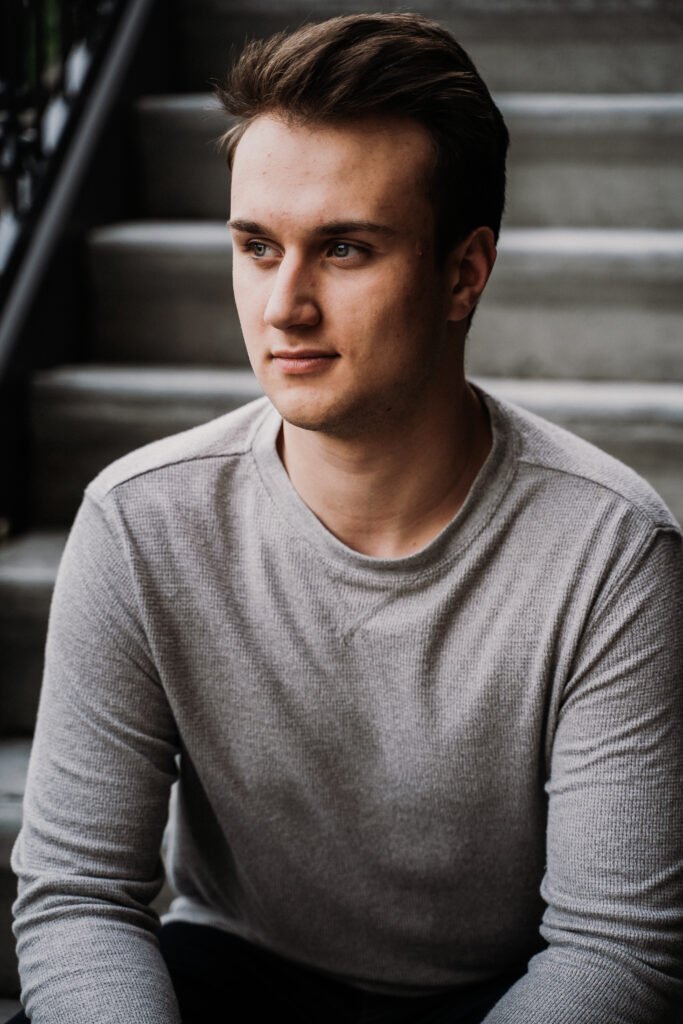 Senior guy in a gray sweater sitting on concrete stairs