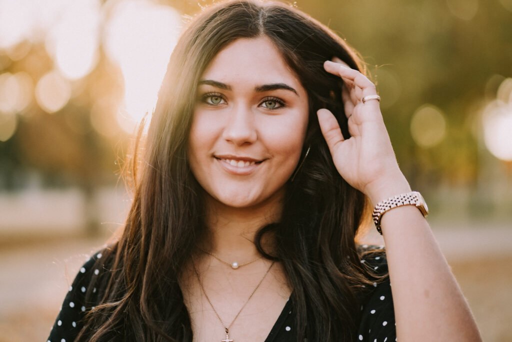 Senior girl smiling in golden fall light in front of Old Main at the University of Arkansas