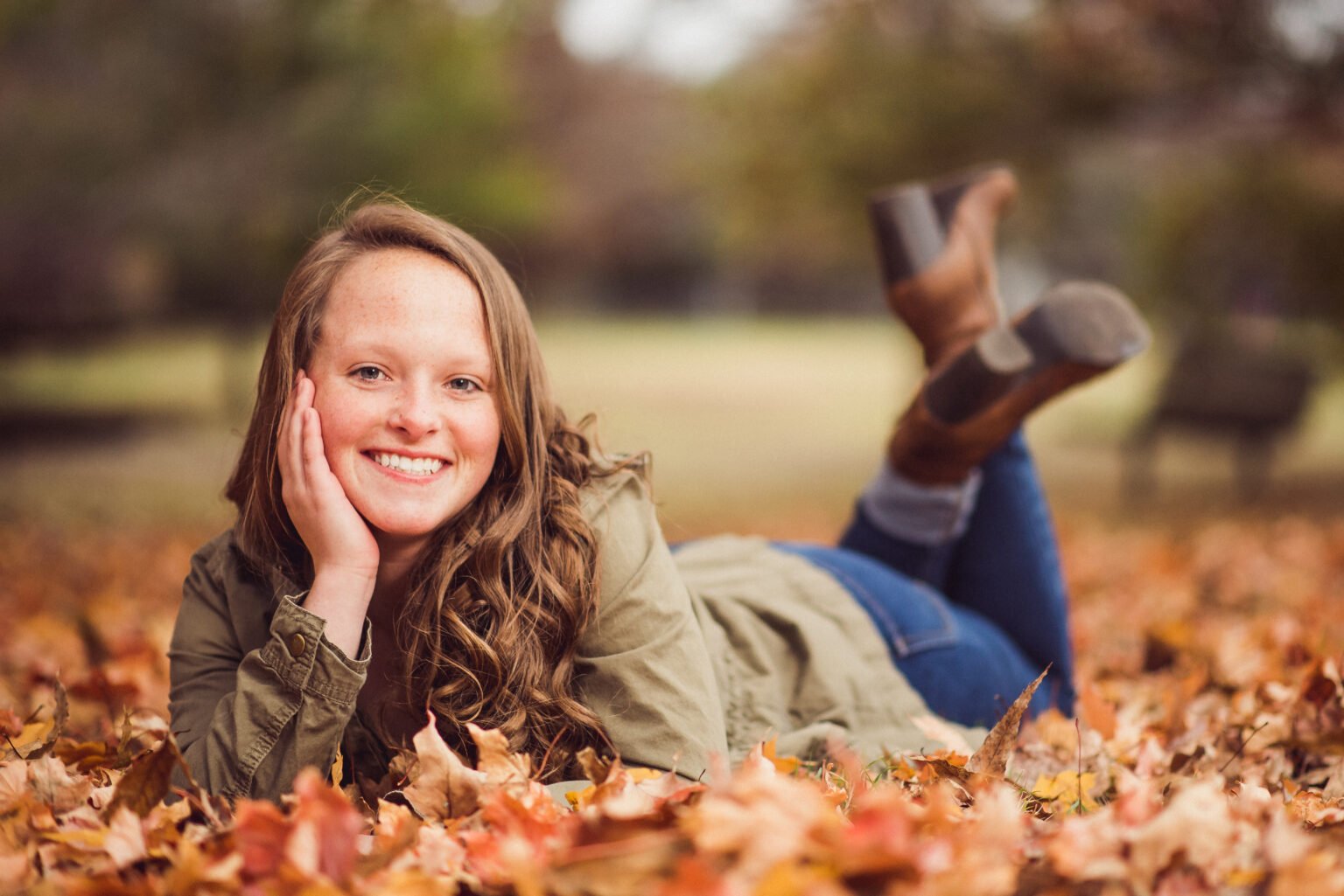 Senior girl lying in fall leaves with her feet up at Gulley Park, Fayetteville senior pictures