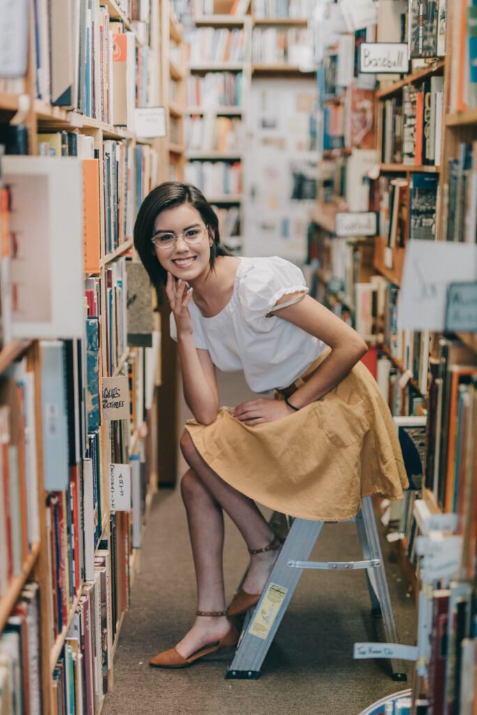 Artsy senior portrait among tall shelves of books