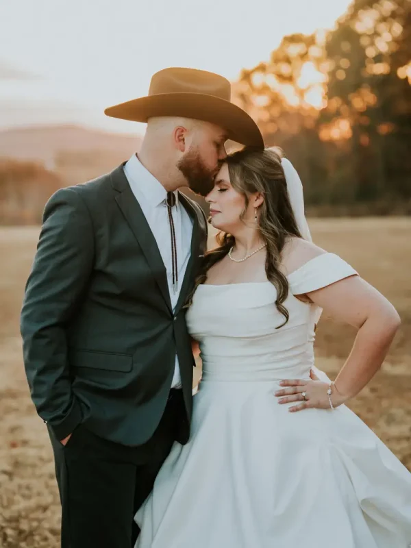 Groom in a grey suit kissing his bride outdoors