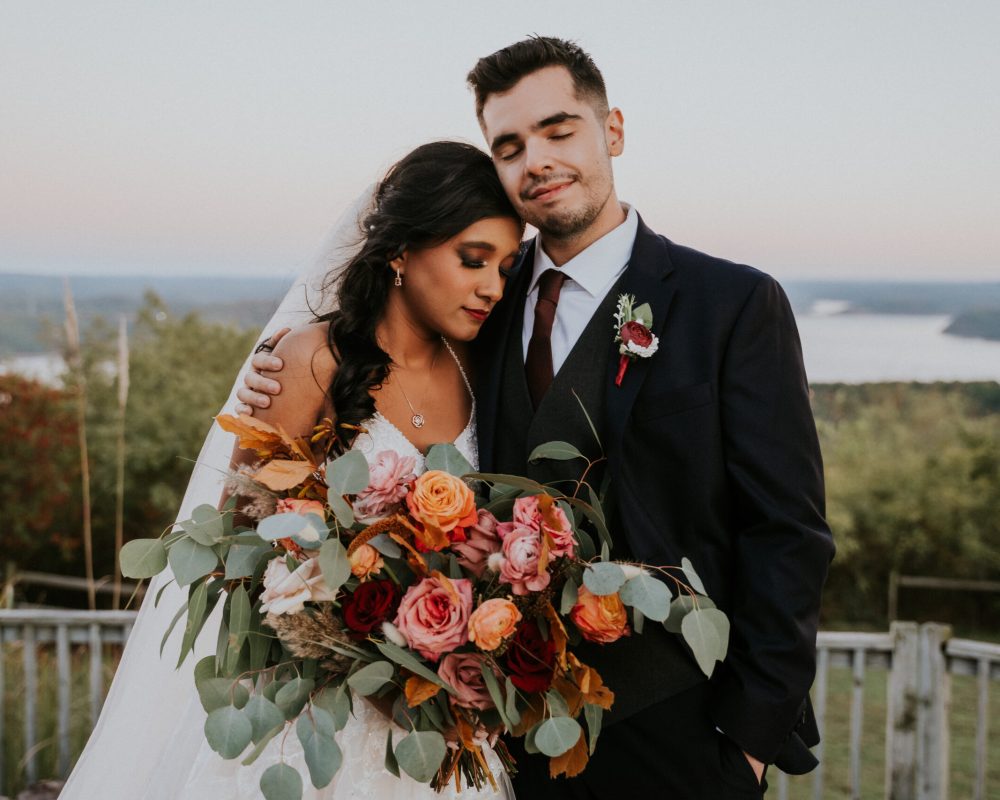 groom hugging bride lake view