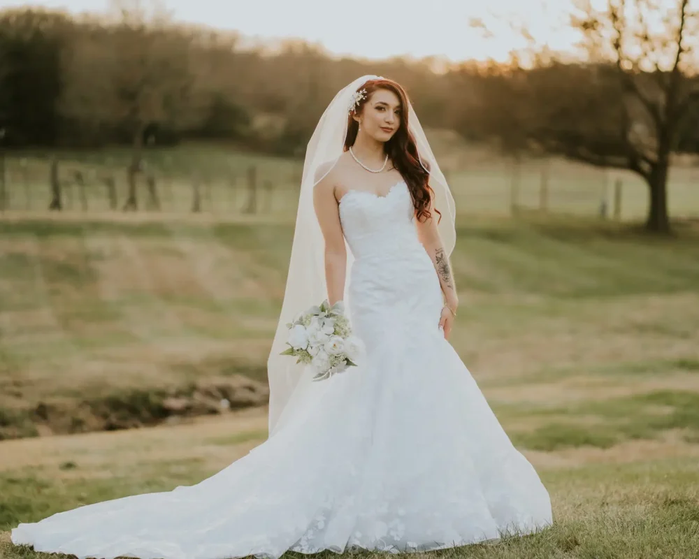 Bride posing elegantly at Sassafras Vineyard in Springdale, AR, with the stunning backdrop of a sunset.