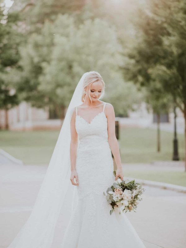 Bride in a veil and lace gown holding her bouquet during a bridal session